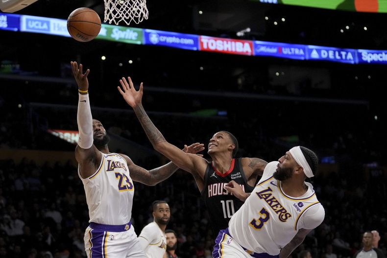 LeBron James (23), de los Lakers de Los Ángeles, Jabari Smith Jr. (10), de los Rockets de Houston y Anthony Davis (3) pelean por un rebote durante la primera mitad del juego de baloncesto de la NBA, en Los Ángeles, el domingo 19 de noviembre de 2023. (AP Foto/Eric Thayer)