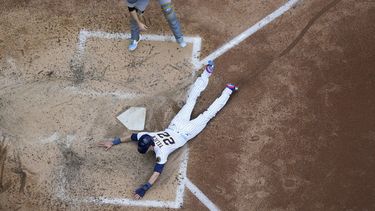 Christian Yelich de los Cerveceros de Milwaukee anota una carrera ante el receptor Jason Delay de los Piratas de Pittsburgh, el domingo 18 de julio de 2023, en Milwaukee. (AP Foto/Morry Gash)