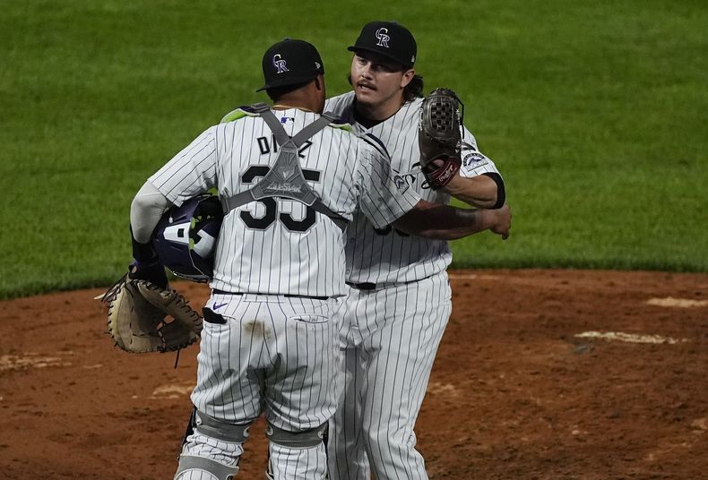 El receptor venezolano de los Rockies de Colorado, Elías Díaz (al frente), felicita al relevista Victor Vodnik luego del juego de béisbol ante los Mets de Nueva York, el martes 6 de agosto de 2024, en Denver. (AP Foto/David Zalubowski)