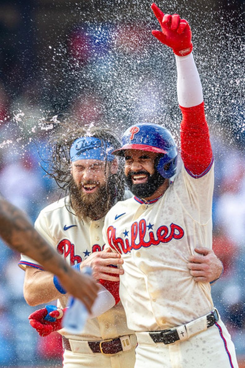 Derek Hill, derecha, de los Filis de Filadelfia, celebra con Brandon Marsh después de batear el sencillo decisivo en la 12da entrada del juego de béisbol de Grandes Ligas ante los Azulejos de Toronto, el domingo 9 de agosto de 2026, en Filadelfia. (AP Foto/Laurence Kesterson)