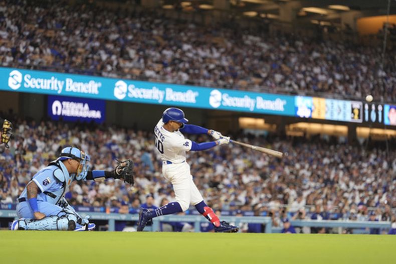 Mookie Betts, de los Dodgers de Los Ángeles, batea un jonrón solitario delante del catcher venezolano Salvador Pérez, de los Reales de Kansas City, el miércoles 12 de agosto de 2026 (AP Foto/Mark J. Terrill)