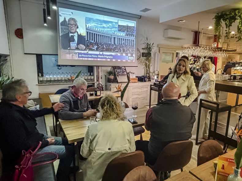 Periodistas y residentes de Schiavon, un poblado del norte de Italia y pueblo natal del cardenal Pietro Parolin, se reúnen en el Caffe Centrale, el miércoles 7 de mayo de 2025, para seguir la transmisión en vivo del Vaticano, donde el cardenal Parolin preside el cónclave en que será elegido el sucesor del papa Francisco. (AP Foto/Colleen Barry)