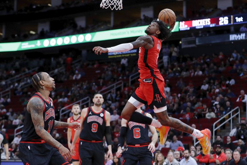 El base de los Rockets de Houston Jalen Green clava el balón mientras lo observan el alero de los Bulls de Chicago DeMar DeRozan, el pívot Nikola Vucevic y el base Alex Caruso el jueves 21 de marzo del 2024. (AP Foto/Michael Wyke)
