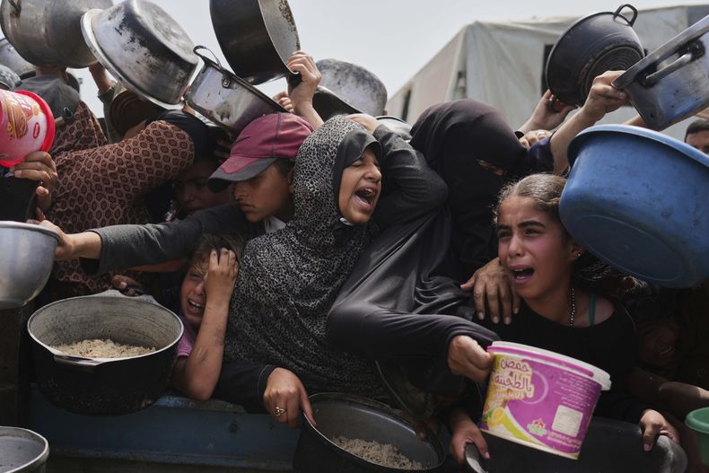 Niños palestinos reciben alimentos donados en un centro de distribución en Jan Yunis, en la Franja de Gaza, el 21 de abril de 2025. (AP Foto/Abdel Kareem Hana)