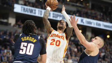 El alero de los Hawks de Atlanta John Collins, al centro, ataca el canasto ante el alero Aaron Gordon y el pívot Nikola Jokic, de los Nuggets de Denver, en la primera mitad del partido del sábado 4 de febrero de 2023, en Denver. (AP Foto/David Zalubowski, Archivo)