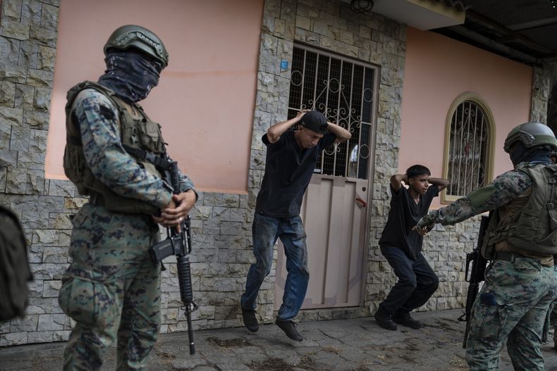 Soldados obligan a dos hombres a ejercitarse como castigo por no tener permisos para sus motocicletas, en la ciudad de Durán, ubicada frente a Guayaquil, Ecuador, el 30 de septiembre de 2023. (AP Foto/Rodrigo Abd)