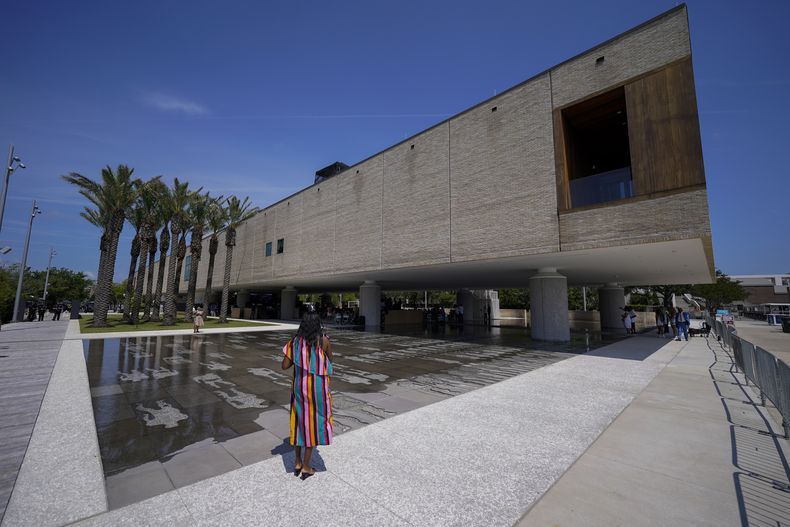 Una visitante toma una fotografía durante la inauguración del Museo Internacional Afroestadounidense el sábado 24 de junio de 2023, en Charleston, Carolina del Sur. Con vistas al antiguo muelle por el que casi la mitad de la población esclavizada entró por primera vez a Norteamérica, el museo alberga exposiciones y piezas que muestran cómo el trabajo, la perseverancia, la resistencia y las culturas de los afroestadounidenses dieron forma a las Carolinas, al país y al mundo. (AP Foto/Chris Carlson)