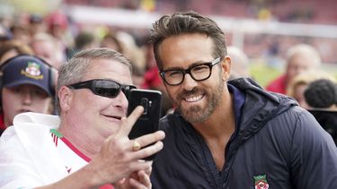 Ryan Reynolds, codueño del Wrexham, posa con aficionados previo al partido contra Boreham Wood en la National League, el sábado 22 de abril de 2023. (Martin Rickett/PA vía AP)