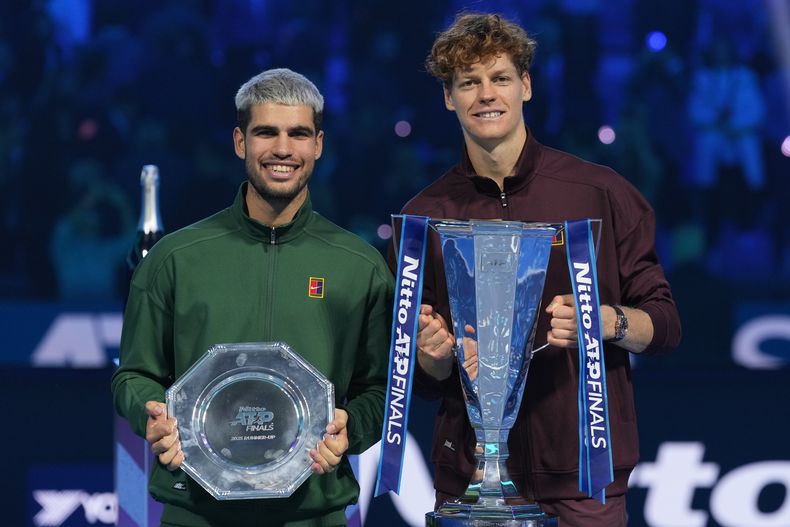 Carlos Alcaraz, a la izquierda, y el ganador Jannik Sinner se paran en el podio después del juego final de tenis de las Finales del ATP World Tour, en Turín, Italia, el domingo 16 de noviembre de 2025. (AP Photo/Antonio Calanni)
