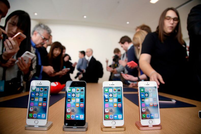 ARCHIVO- En esta imagen de archivo del 21 de marzo de 2016, varios miembros de los medios e invitados dan un vistazo al nuevo iPhone SE en un evento en las oficinas generales de Apple en Cupertino, California. (AP Foto/Marcio Jose Sanchez, Archivo)