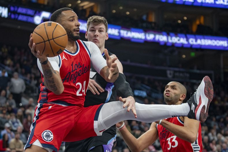 Norman Powell, de los Clippers de Los Ángeles, busca enviar un pase frente a Kyle Filipowski, del Jazz de Utah, en el encuentro del jueves 13 de febrero de 2025 (AP Foto/Rick Egan)