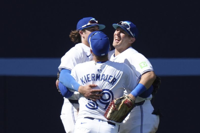 Los jardineros de los Azulejos de Toronto, Daulton Varsho, derecha, Kevin Kiermaier, centro y Addison Barger, izquierda, celebran después de conseguir la victoria sobre los Guardianes de Cleveland en el juego de béisbol en Toronto, el domingo 16 de junio de 2024. (Chris Young/The Canadian Press vía AP)