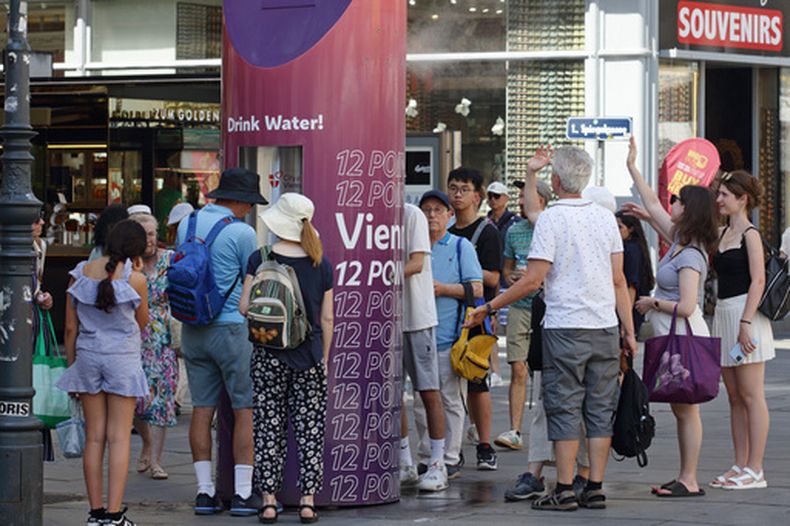 Varias personas forman una fila para rellenar botellas de agua en un caluroso día de verano en el centro de la ciudad de Viena, Austria, el sábado 27 de junio de 2026. (AP Foto/Heinz-Peter Bader)
