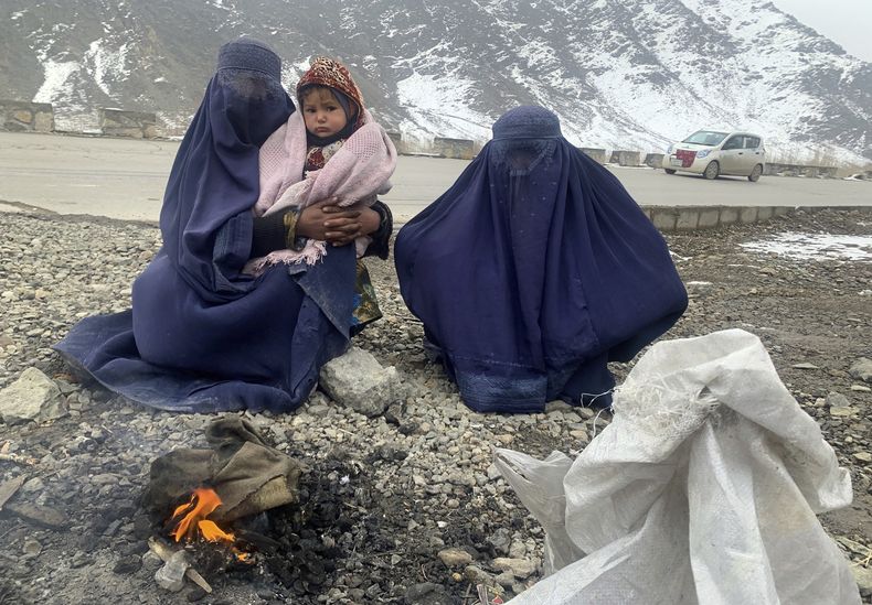 Dos mujeres afganas con un bebé se calientan cerca de una hoguera en Kabul, Afganistán, el 18 de enero de 2022. (AP Foto/Kathy Gannon, Archivo)