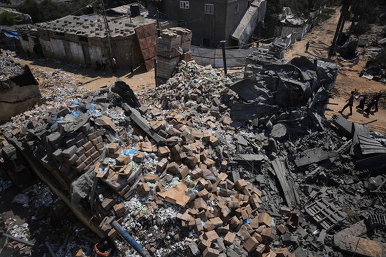 Palestinos pasan junto a un almacén de distribución de alimentos dañado en un ataque israelí contra una vivienda cercana en Deir al-Balah, en el centro de la Franja de Gaza, el 26 de agosto de 2026. (AP Foto/Abdel Kareem Hana)