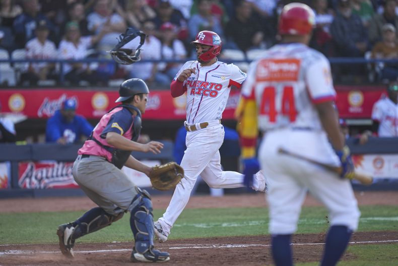 Mario Feliciano, centro, de Puerto Rico, anota una carrera en contra de Japón durante el juego de béisbol de la Serie del Caribe, en el estadio Nido de las Águilas en Mexicali, México, el domingo 2 de febrero de 2025. (AP Foto/Fernando Llano)