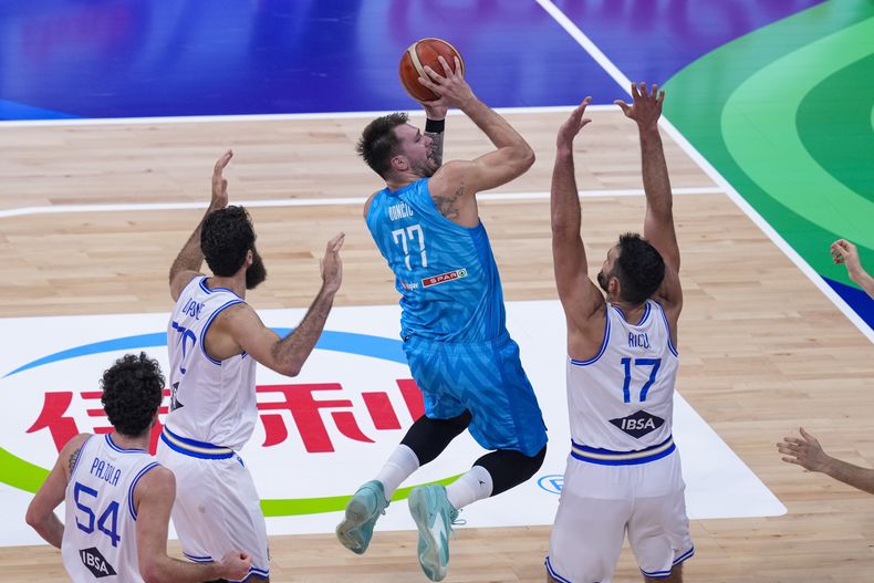 El base de Eslovenia Luka Doncic lanza el balón sobre el italiano Giampaolo Ricci (17) en el encuentro de clasificación de la Copa Mundial de Baloncesto en Manila el sábado 9 de septiembre del 2023. (AP Foto/Michael Conroy)