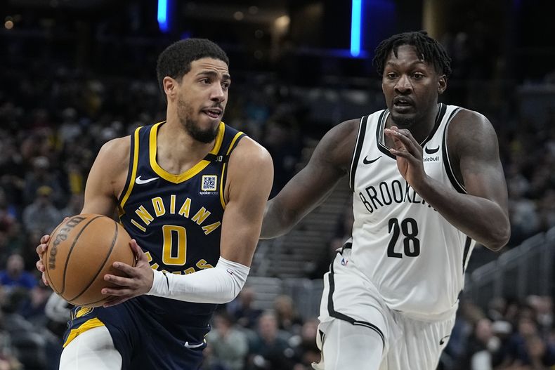Tyrese Haliburton (0), de los Pacers de Indiana, se enfila hacia la canasta con la persecusión de Dorian Finney-Smith (28), de los Nets de Brooklyn, durante la segunda mitad del juego de baloncesto de la NBA, el lunes 1 de abril de 2024, en Indianápolis. (AP Foto/Darron Cummings)