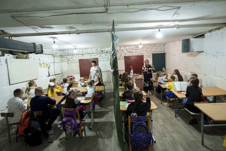 Alumnos escuchan a sus profesores durante una clase en el sótano de un edificio municipal durante el primer día de clases, en Bobryk, región de Sumy, Ucrania, el lunes 1 de septiembre de 2025. La escuela de Bobryk se vio obligada a trasladarse al sótano debido a las constantes alarmas. (AP Foto/Evgeniy Maloletka)