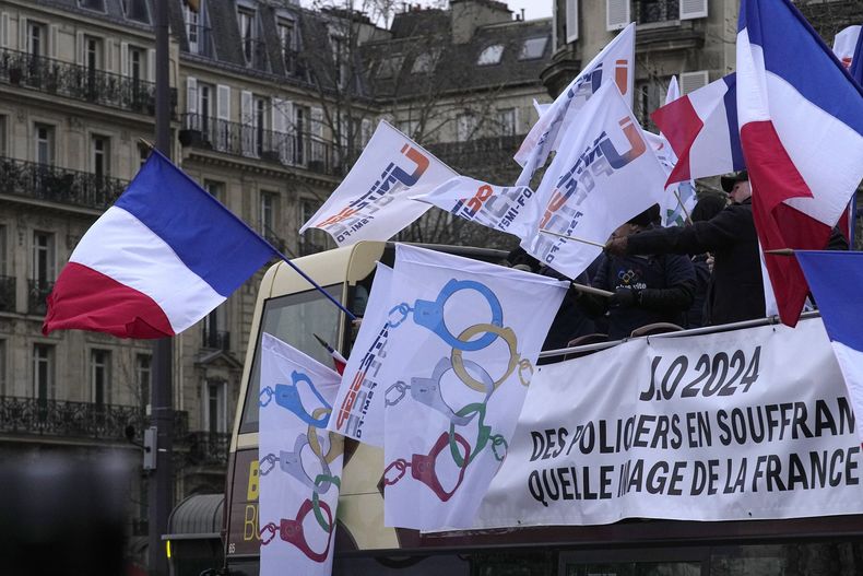 Policías de París se manifiestan con banderas que convierten los anillos olímpicos en esposas, el 10 de enero de 2024. Los agentes que cumplan funciones en los Juegos Olímpicos de París recibirán pagos especiales, se informó el martes 30 de enero de 2024. (AP Foto/Michel Euler)