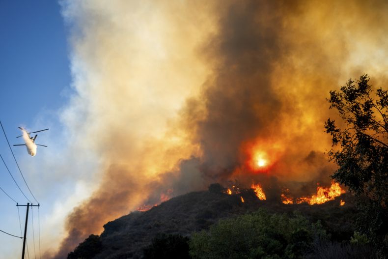 Un helicóptero deja caer agua sobre un incendio a lo largo de la autopista South Mountain Rd., el jueves 7 de noviembre de 2024, en Santa Paula, California. (AP Foto/Noah Berger)