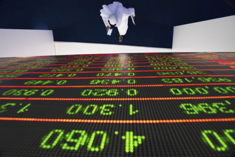 ARCHIVO - Un emiratí camina bajo una pantalla que muestra las cotizaciones en el Mercado Financiero de Dubái, Emiratos Árabes Unidos, el 10 de octubre de 2019. (AP Foto/Jon Gambrell, Archivo)