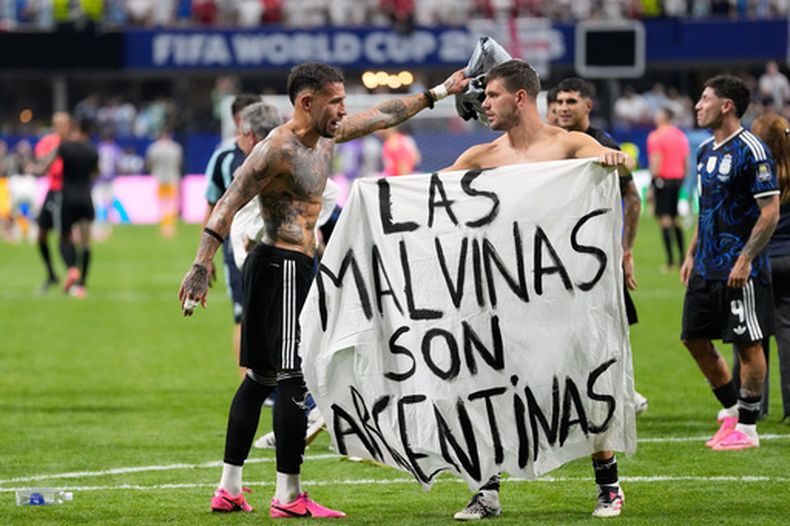 El volante argentino Giovani Lo Celso sostiene una pancarta con la frase Las Malvinas son argentinas junto a su compañero Nicolás Otamendi al término de la victoria 2-1 ante Inglaterra en las semifinales de la Copa del Mundo, el miércoles 15 de julio de 2026, en Atlanta. (AP Foto/Rebecca Blackwell)