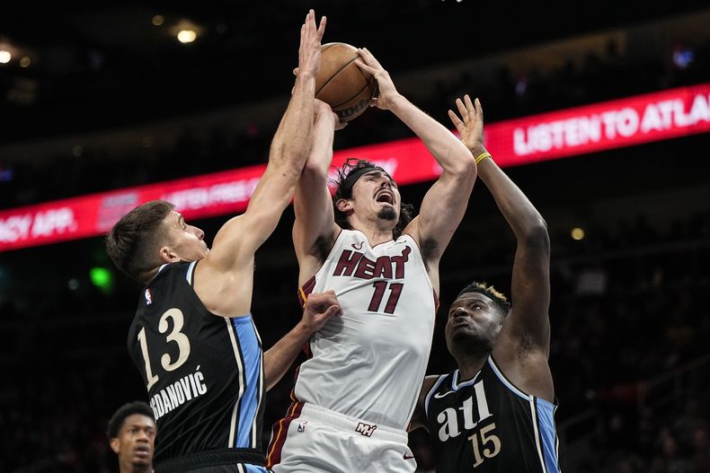 El mexicano Jaime Jáquez Jr. (11), del Heat de Miami, dispara entre Bogdan Bogdanovic y Clint Capela, de los Hawks de Atlanta, en el encuentro del sábado 11 de noviembre de 2023 (AP Foto/Mike Stewart)