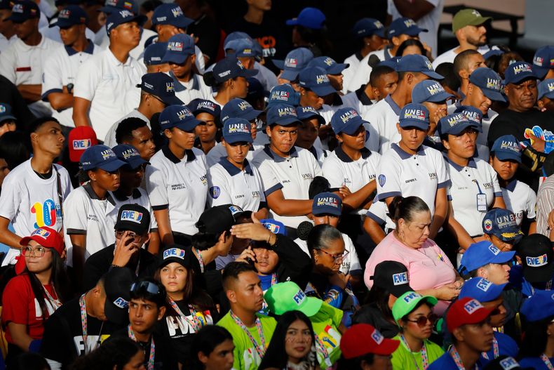 Estudiantes de la Universidad Experimental de Seguridad Nacional, con gorras azules, asisten a un evento del Día del Estudiante en el palacio presidencial de Miraflores en Caracas, Venezuela, el viernes 21 de noviembre de 2025. (Foto AP/Cristian Hernández)