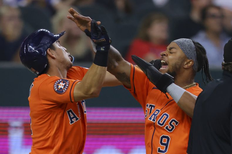 Mauricio Dubón, izquierda, y Corey Julks, derecha, celebran después de anotar con un triple de Chas McCormick en la octava entrada del juego de béisbol en contra de los Rangers de Texas, el domingo 2 de julio de 2023, en Arlington, Texas. (AP Foto/Gareth Patterson)