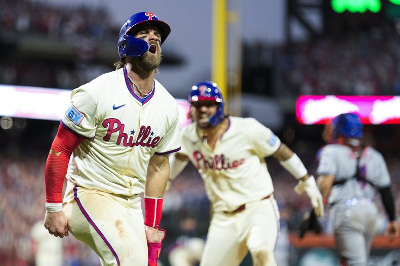 Bryce Harper, izquierda, y Nick Castellanos, de los Filis de Filadelfia, celebran después de un triple de dos carreras de Bryson Stott durante la octava entrada del Juego 2 de una Serie Divisional de la Liga Nacional dcontra los Mets de Nueva York, el domingo 6 de octubre de 2024, en Filadelfia. (AP Foto/Matt Slocum)