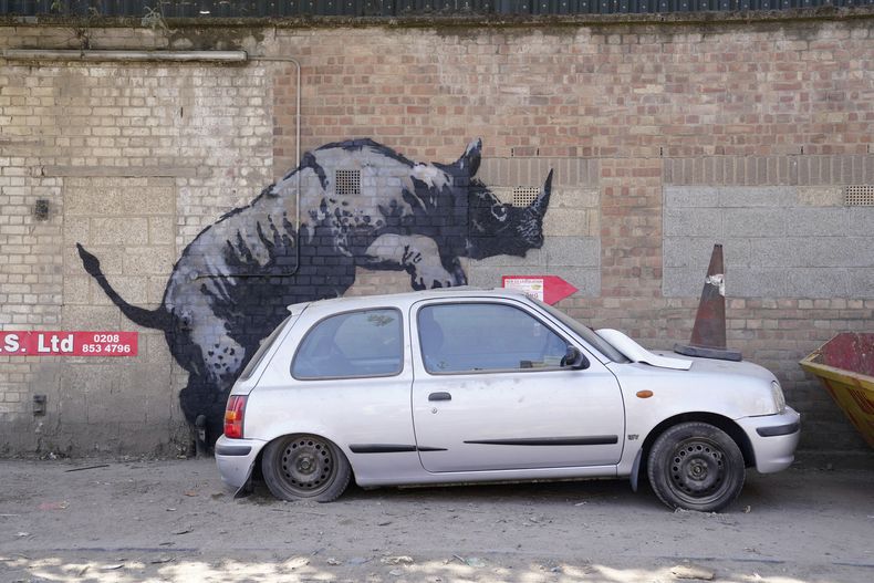 Una nueva obra de arte presentada por Banksy, que representa un rinoceronte que parece subirse a un automóvil, la octava obra de arte de su colección de temática animal, en Westmoor Street en Charlton, sureste de Londres, el lunes 12 de agosto de 2024. (Lucy North/PA via AP)