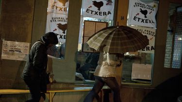 americateve | Dos personas pasan junto a un bar en el que hay carteles que piden que todos los miembros de la proscrita organizaci&oacute;n vasca ETA regresen a las c&aacute;rceles, en Tafalla, Navarra, el mi&eacute;rcoles 23 de octubre del 2013. Miles de personas se r