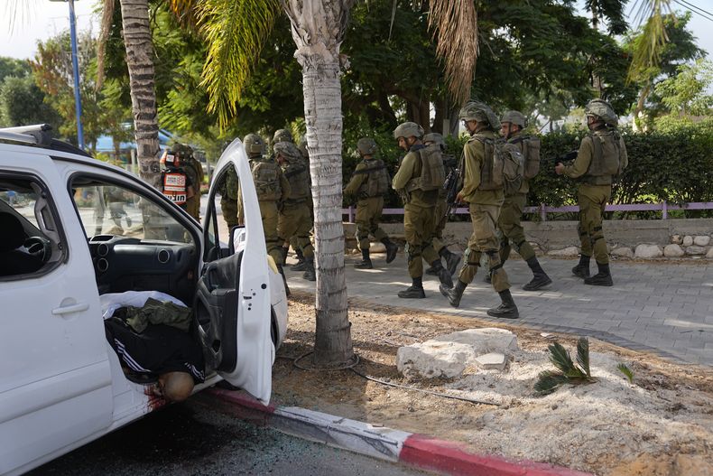 Soldados israelíes pasan junto a un civil asesinado por insurgentes de Hamás en Sderot, Israel, el 7 de octubre de 2023. Insurgentes de Hamás en la Franja de Gaza se infiltraron en el sur de Israel y dispararon miles de proyectiles al país mientras Israel comenzaba a atacar objetivos en el enclave palestino en respuesta. (AP Foto/Ohad Zwigenberg)