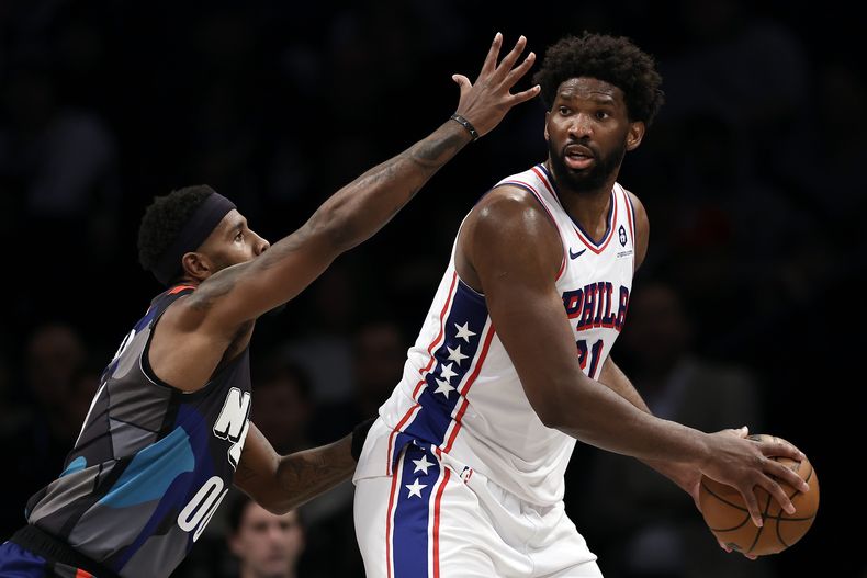 El pívot Joel Embiid, derecha, de los 76ers de Filadelfia, busca mandar un pase mientras el alero de los Nets de Brooklyn Royce ONeale lo presiona, durante la segunda mitad del juego de baloncesto de la NBA, el domingo 19 de noviembre de 2023, en Nueva York. (AP Foto/Adam Hunger)