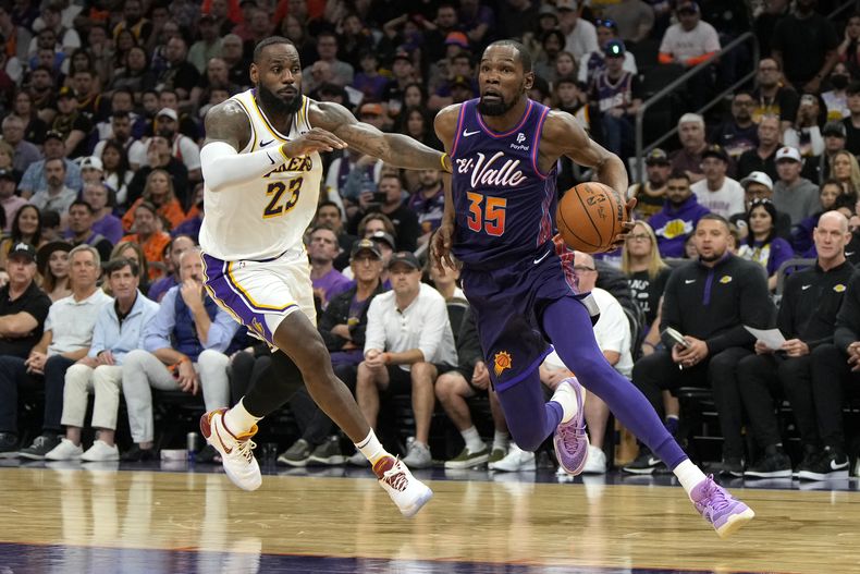 Kevin Durant (35) de los Suns de Phoenix avanza con el balón ante LeBron James de los Lakers de Los Ángeles, el domingo 25 de febrero de 2024, en Phoenix. (AP Foto/Rick Scuteri)