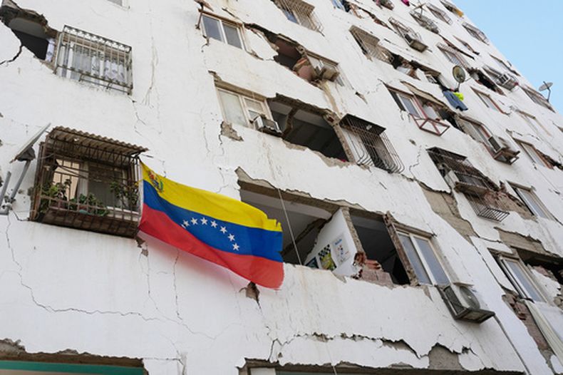 Una bandera venezolana cuelga de un edificio dañado por fuertes sismos en Catia La Mar, Venezuela, el viernes 26 de junio de 2026. (AP Foto/Fernando Vergara)