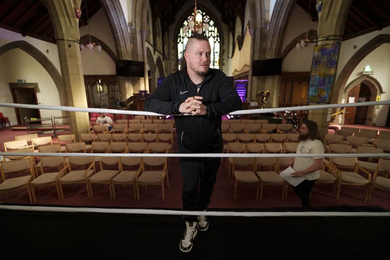Gareth Angel Thompson, fundador del organismo de beneficencia Kingdom Wrestling, permanece a un costado del cuadrilátero en la iglesia de San Pedro antes de uno de los espectáculos mensuales de lucha libre que organiza allí el grupo que encabeza, el sábado 29 de marzo de 2025, en Shipley, Reino Unido. (AP Foto/Jon Super)