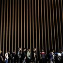 ARCHIVO - Personas formadas junto a un muro fronterizo mientras esperan solicitar asilo en Estados Unidos tras cruzar la frontera desde México, el martes 11 de julio de 2023, cerca de Yuma, Arizona. (AP Foto/Gregory Bull, Archivo)