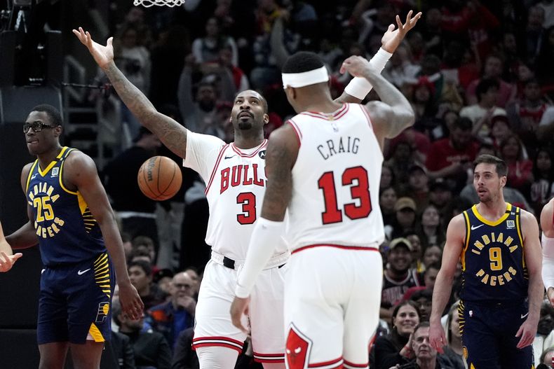 El pívot de los Bulls de Chicago Andre Drummond (3) celebra luego de anotar; el alero Jalen Smith (izquierda), y el armador T.J. McConnell (9) de los Pacers de Indiana reaccionan durante la segunda mitad del juego de baloncesto de la NBA, en Chicago, el miércoles 27 de marzo de 2024. (AP Foto/Nam Y. Huh)