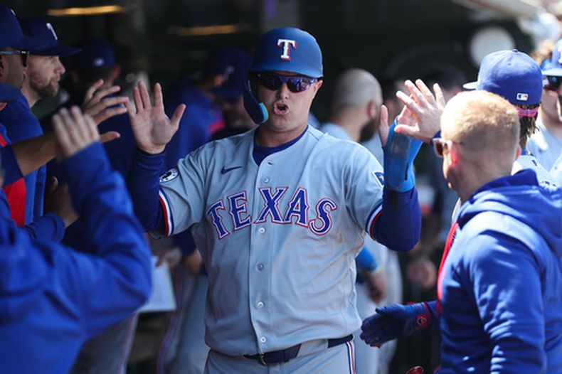 Joc Pederson, de los Rangers de Texas, festeja en el dugout luego de anotar ante los Atléticos en el juego del jueves 16 de abril de 2026 (AP Foto/Scott Marshall)