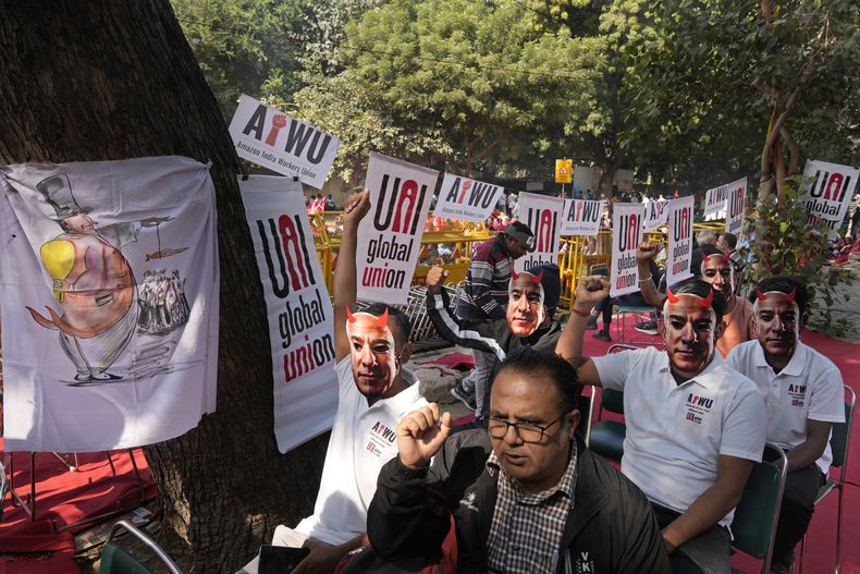 Participantes de una protesta portan máscaras con la imagen del dueño de Amazon, Jeff Bezos, al tiempo que trabajadores de almacén y conductores de entrega se congregaron en la capital, Nueva Delhi, India, para exigir mejores salarios y condiciones laborales, el viernes 29 de noviembre de 2024. (AP Foto/Manish Swarup)