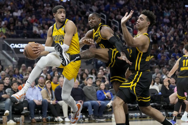 El escolta de los Pacers de Indiana, Tyrese Haliburton, a la izquierda, busca pasar el balón mientras el alero de los Warriors de Golden State. Jonathan Kuminga, en el centro, y el alero Trayce Jackson-Davis defienden durante la segunda mitad de un partido de baloncesto de la NBA en San Francisco, el viernes 22 de marzo de 2024. (AP Foto/Jeff Chiu)