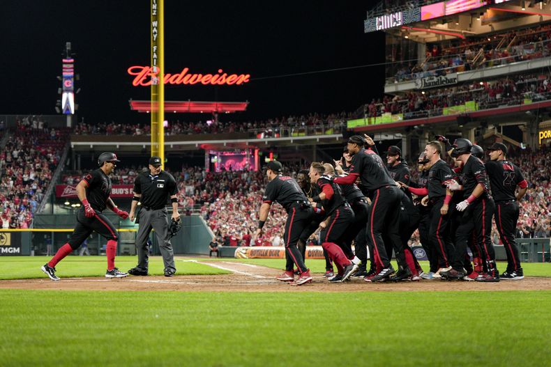 Christian Encarnacion-Strand, izquierda, de los Rojos de Cincinnati, es esperado por sus compañeros en el plato después de batear el cuadrangular con el que su equipo dejó tendidos en el terreno a los Azulejos de Toronto, en la novena entrada del juego de béisbol del viernes 18 de agosto de 2023. (AP Foto/Jeff Dean)