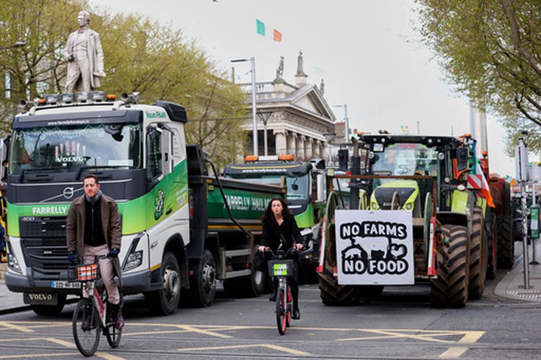 Ciclistas pasan junto a tractores que bloquean la calle OConnell en el quinto día de una protesta nacional contra el precio del combustible, en Dublín, Irlanda, el sábado 11 de abril de 2026. (Foto AP/Peter Morrison)