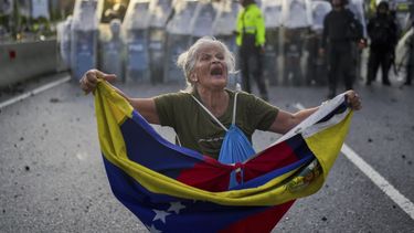 Consuelo Márquez con una bandera de Venezuela al frente de la policía que bloquea las manifestaciones contra los resultados de las elecciones que dieron por ganador a Nicolás Maduro, el día después de las votaciones en Caracas, Venezuela, el lunes 29 de julio de 2024. (AP Foto/Matías Delacroix)