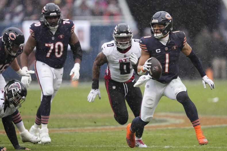 El quarterback de los Bears de Chicago Justin Fields (1) traslada el ovoide durante la primera mitad del juego de NFL ante los Falcons de Atlanta, en Chicago, el domingo 31 de diciembre de 2023. (AP Foto/Charles Rex Arbogast)
