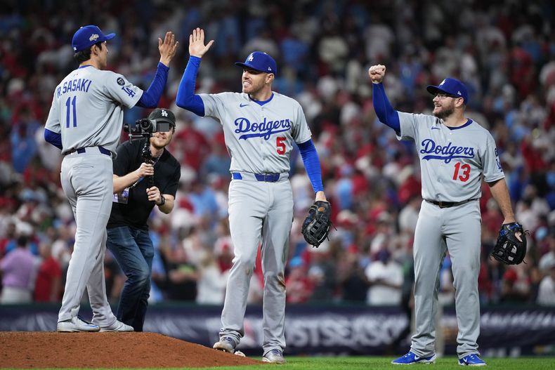 Roki Sasaki, izquierda, relevista de los Dodgers de Los Ángeles, celebra con el primera base freddie Freeman, centro, y el tercera base Max Muncy después de la victoria en el segundo juego de la Serie Divisional de la Liga Nacional frente a los Filis de Filadelfia, el lunes 6 de octubre de 2025, en Filadelfia. (AP Foto/Matt Slocum)