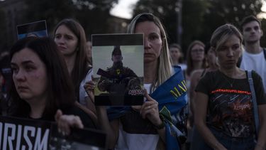 Una mujer sostiene una foto de un soldado ucraniano durante un encuentro ante la embajada rusa en Kiev, Ucrania, el sábado 29 de julio de 2023 para conmemorar el primer aniversario del ataque a un edificio penitenciario en Olenivka, en el este de Ucrania, que mató a docenas de presos militares ucranianos. (AP Foto/Jae C. Hong)