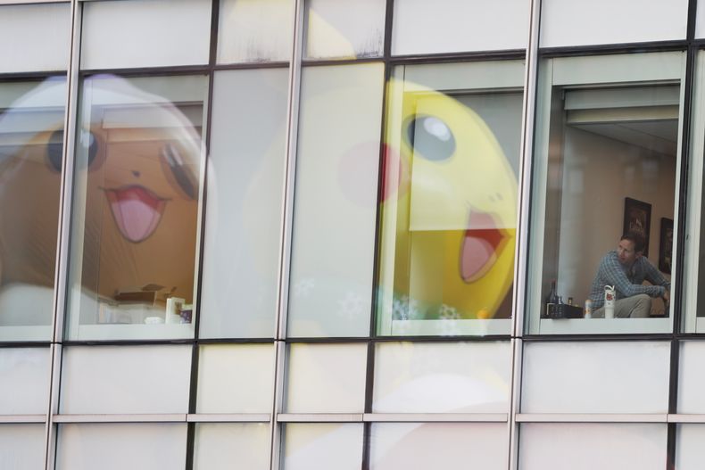 Gente dentro de edificios de oficinas observa cómo pasa el globo de Pikachu durante el Desfile del Día de Acción de Gracias de Macys, el jueves 27 de noviembre de 2025, en Nueva York. (Foto AP/Heather Khalifa)